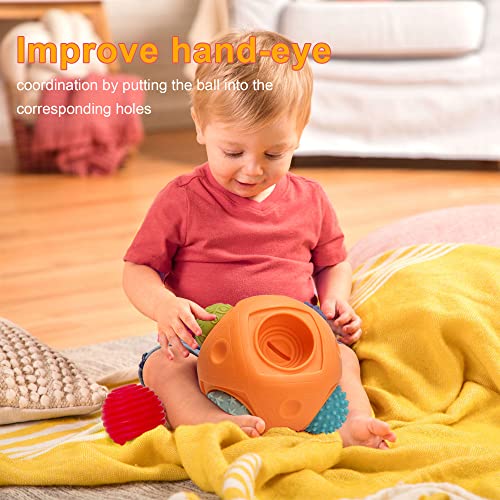 A baby plays with the Toyfetti Montessori Sensory Wonder Ball – Educational Textured Ball Set for Babies & Toddlers on a yellow blanket. Text reads, “Improve hand-eye coordination and fine motor skills by matching the ball to the correct holes.”.