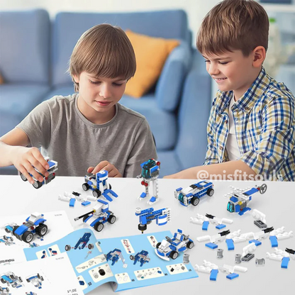 Two children sit at a table building blue and white vehicles with the Toyfetti Misfit BuildMaster 30-in-1 STEM Building Blocks Set (150+ pieces); completed models and instructions are spread out before them.