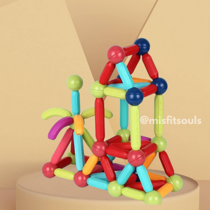 MagniBlocks™ by Toyfetti magnetic building blocks are assembled into playful shapes like a bicycle and geometric figure, set against a soft beige background. Image features @misfitsouls.
