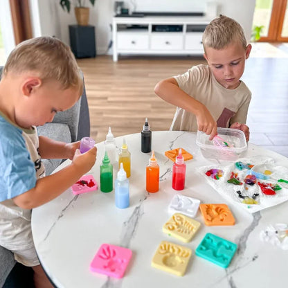 Two boys enjoy hands-on fun at a white table, creating colorful 3D animals with the Toyfetti Magic Water Wonder Kit using water, paints, and silicone molds for a bright sensory art project.