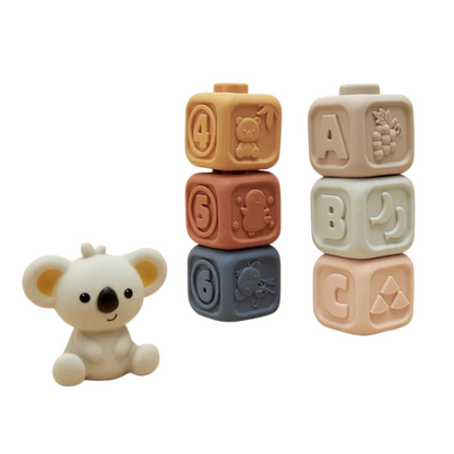 The Toyfetti CubbyKoala – Soft Silicone Teether & Stacking Toy Set for Babies features a cute koala teether and three pastel blocks with embossed letters, numbers, and animal shapes for sensory play.