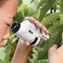 A person closely examines a green leaf with the Kids Pocket Microscope – Compact LED Microscope, exploring nature outdoors with this portable science tool.