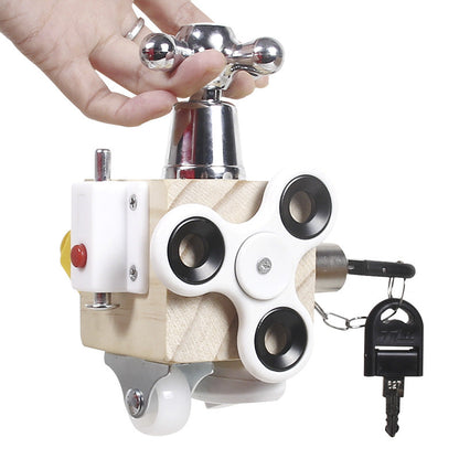 A hand holds the Toyfetti Montessori Lock & Key Learning Cube—a hands-on sensory toy with a faucet handle, fidget spinner, red button, caster wheel, and key on a chain—perfect for building kids’ fine motor skills.