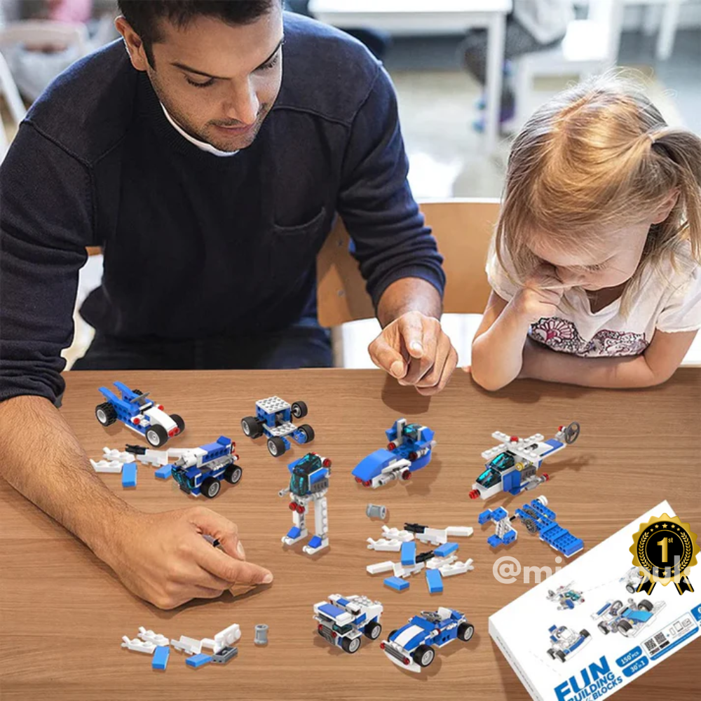 An adult and a girl build blue and white vehicles with the Toyfetti Misfit BuildMaster 30-in-1 STEM Building Blocks Set (150+ pieces) at a table, focused on their creations, while a FUN-labeled box sits in the corner.