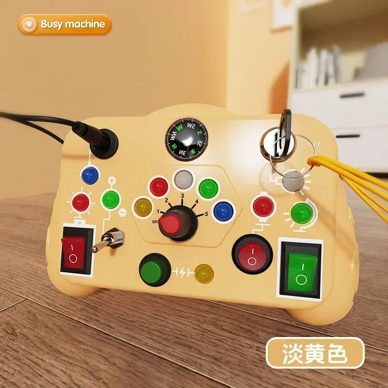The Toyfetti BusyBoard Logic & Light Panel is a Montessori switch board for curious kids, designed for sensory play with buttons, switches, dials, indicator lights, a compass, and keyrings. Shown on a wooden floor with a blurred background.