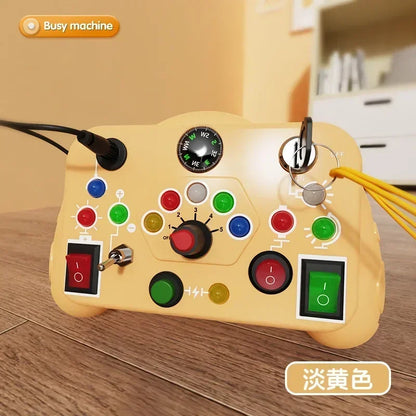 The Toyfetti BusyBoard Logic & Light Panel is a Montessori switch board for curious kids, designed for sensory play with buttons, switches, dials, indicator lights, a compass, and keyrings. Shown on a wooden floor with a blurred background.
