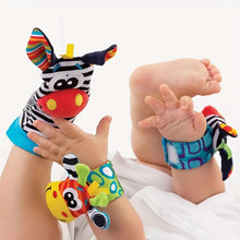 A baby enjoys sensory play with the Toyfetti Plush Animal Baby Socks & Wrist Rattle Set, featuring zebra and giraffe designs, engaging hands and feet while lying on a white background.
