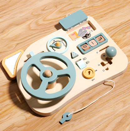 The Toyfetti Montessori Car Press Board is a wooden activity dashboard featuring a blue steering wheel, gear shift, speedometer, knobs, playful illustrations, and a pull string with whistle—designed to build fine motor skills in curious toddlers.