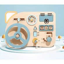 The Toyfetti Montessori Car Press Board – Hands-On Driving Toy for Curious Toddlers features a blue and yellow steering wheel, switches, dials, and buttons on a pastel blue and white board to build fine motor skills.