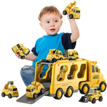 A young child sits on the floor playing with several yellow toy construction vehicles and a matching Toyfetti TruckTrail – Light-Up Vehicle Carrier with Storage, holding one vehicle up and smiling.