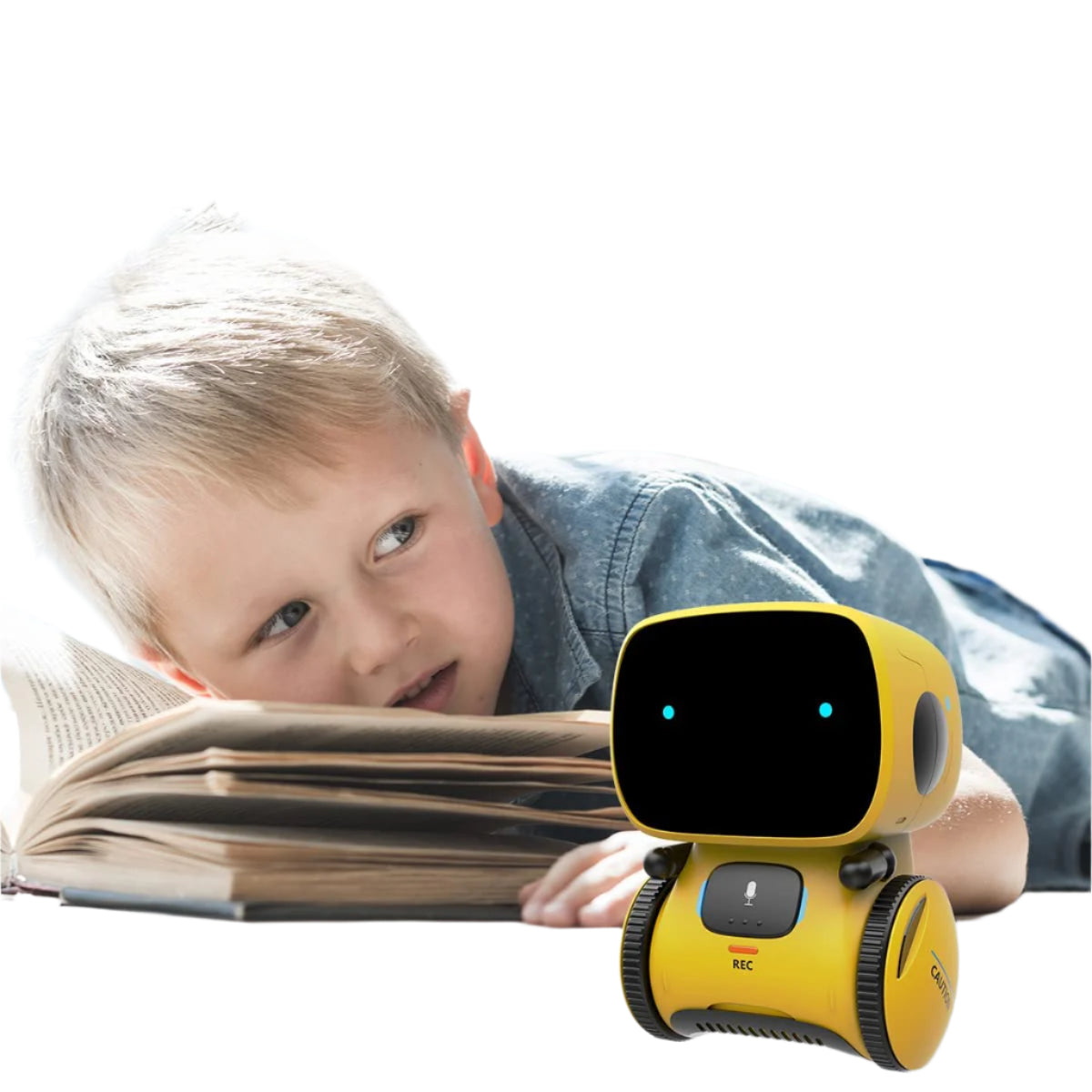 A young boy lies on the floor reading a book, glancing at the Toyfetti Robomate | Jouw Muzikale Vriend - Slimme Robot with its black screen face and glowing blue eyes nearby.