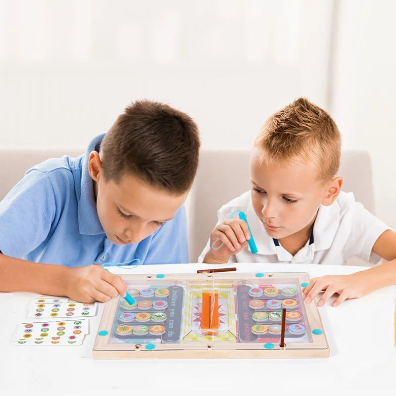 Two young boys sit at a table, focused on Toyfettis Magnetic Maze - Strategy and Coordination Game for Kids. One uses a blue tool as they explore the vibrant game, improving fine motor skills through engaging play with colorful symbols.