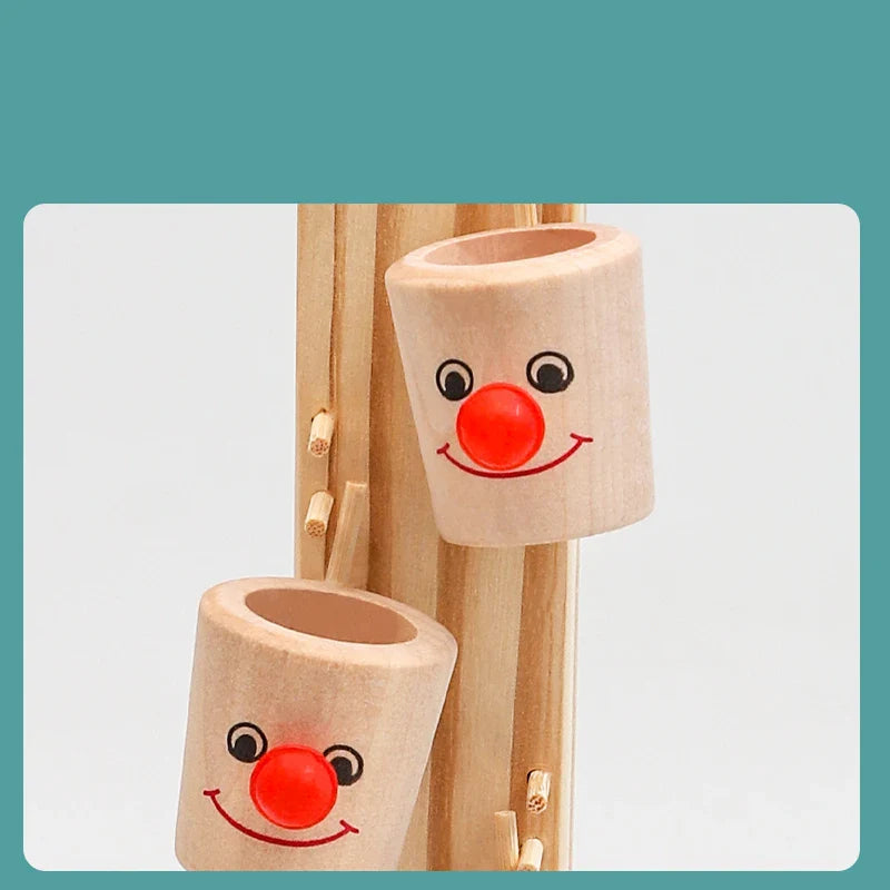 Toyfetti’s Clown Track Wooden Play Tower features two wooden cups with cheerful faces and red noses that slide down a light wood track, inspiring creative play.