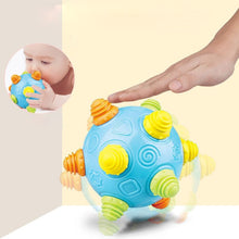 A hand touches the blue Toyfetti Sensory Music Ball – Interactive Light & Sound Toy for Babies and Toddlers, featuring colorful textured knobs. An inset shows a baby engaging with the toy, promoting early development. The scene has a soft, light background.