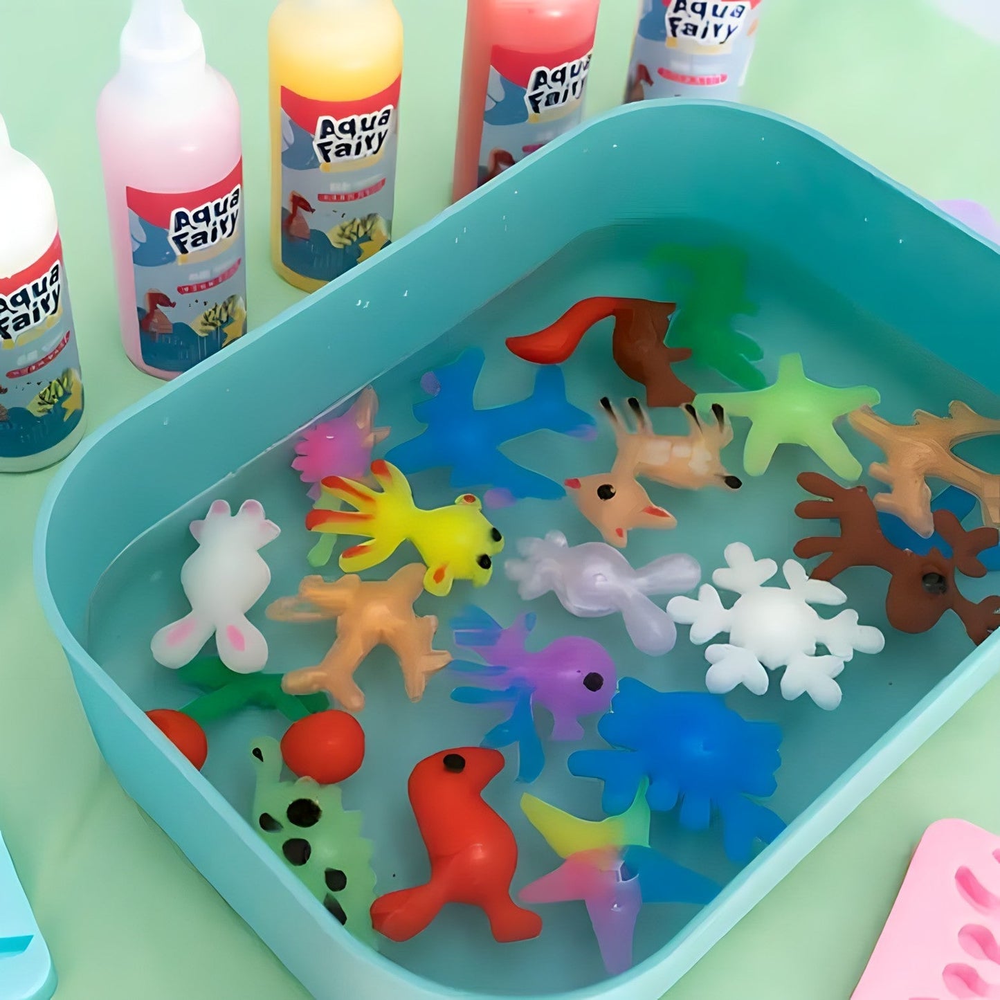 The Toyfetti Magic Water Wonder Kit lets kids create colorful 3D animal figures in water for hands-on sensory fun, with bottles of Aqua Fairy liquid in yellow, pink, and red on a light green surface.